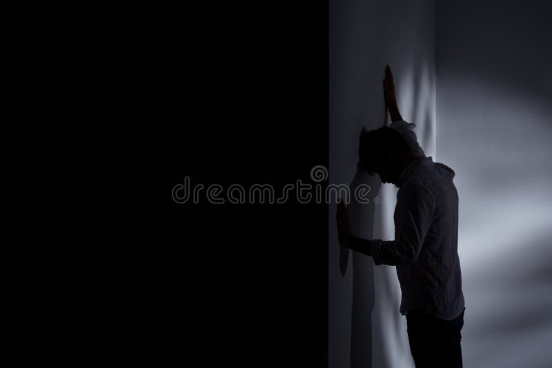 Dark room with sad man leaning against the wall. Dark room with sad man leaning against the wall