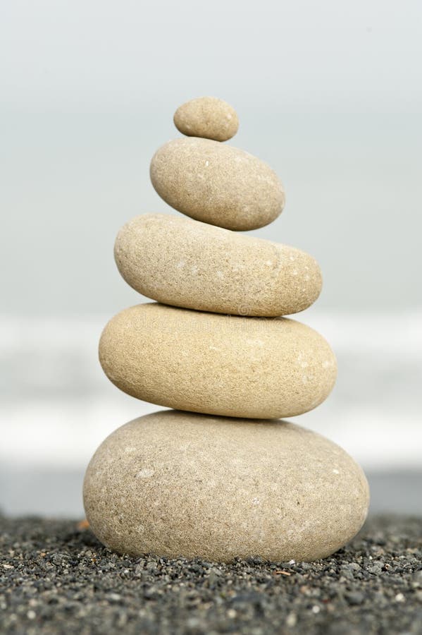 Stack of balanced stones on black sand beach with ocean background. Stack of balanced stones on black sand beach with ocean background