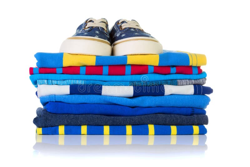 Stapel kleurrijke de zomeroverhemden en een paar tennisschoenen op bovenkant i stock afbeelding Stapel kleurrijke de zomeroverhemden en een paar tennisschoenen op bovenkant i stock afbeelding