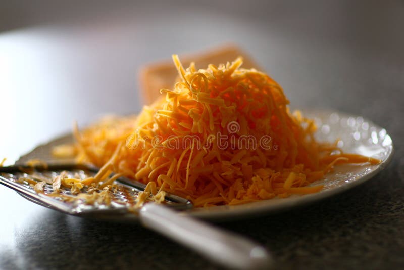 Pile of shredded cheddar cheese on plate. Pile of shredded cheddar cheese on plate