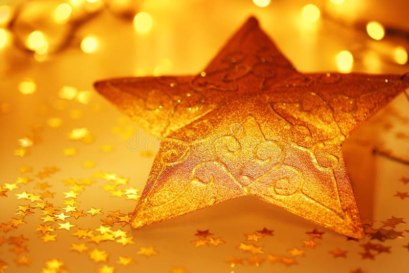 Golden star Christmas tree decoration with winter ornament as holiday background over abstract defocus golden lights