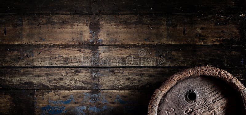 Old oak beer, wine or brandy barrel over a weathered textured wooden wall in a cellar or tavern in panoramic banner format with copy space. Old oak beer, wine or brandy barrel over a weathered textured wooden wall in a cellar or tavern in panoramic banner format with copy space