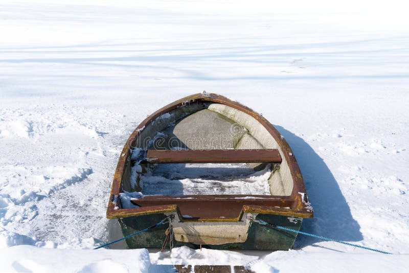 Stara wioślarska łódź w zamarzniętym jeziorze na pogodnym zima dniu, concep
