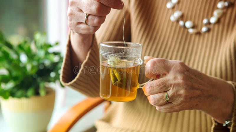 Older woman hand holding a glass of tea with teabag. Older woman hand holding a glass of tea with teabag