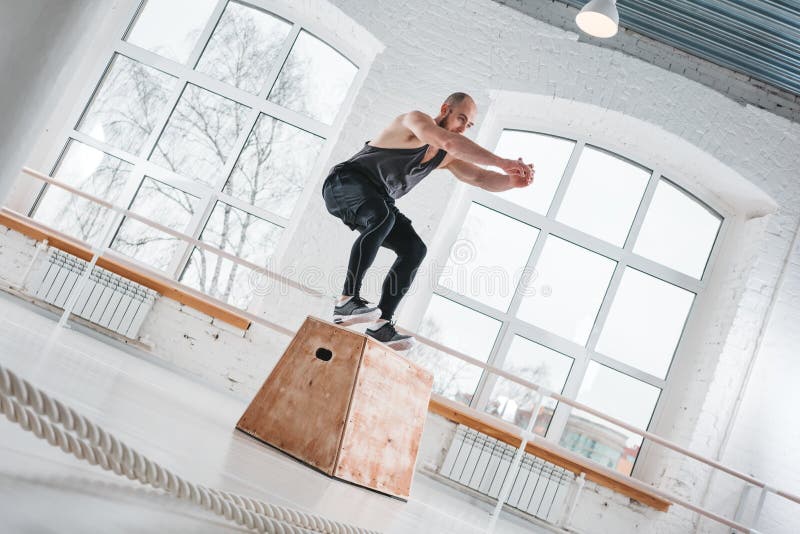 Stark man som gör hoppa övningar över asken på en stilidrottshall för arg utbildning royaltyfri foto Stark man som gör hoppa övningar över asken på en stilidrottshall för arg utbildning royaltyfri foto