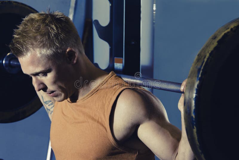 Strong fit man lifting a barbell doing squats with free weights. Strong fit man lifting a barbell doing squats with free weights