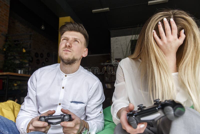 Starker Mann hält gamepad und schaut oben Er ist nerv?s Mädchen hält gamepad auch und bedeckt Gesicht mit der Hand stockfotos Starker Mann hält gamepad und schaut oben Er ist nerv?s Mädchen hält gamepad auch und bedeckt Gesicht mit der Hand stockfotos