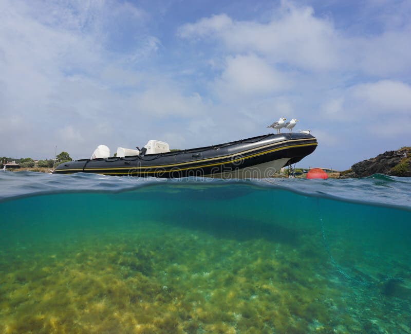 Starres aufblasbares Boot, das mit Möwen unter dem Wasser verputzt ist lizenzfreies stockbild