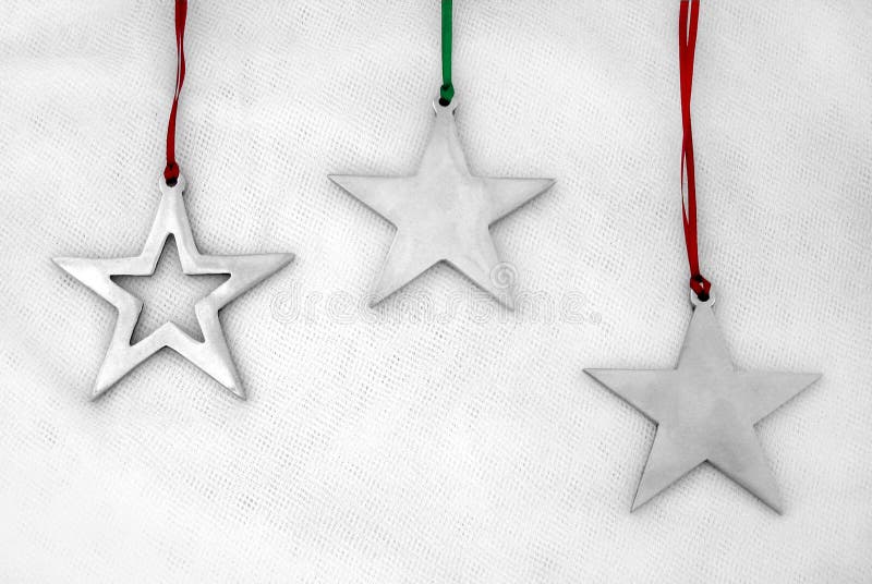 Silver, star-shaped holiday ornaments on red and green ribbons. Silver, star-shaped holiday ornaments on red and green ribbons.