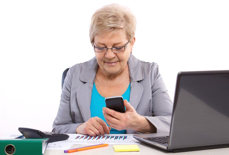 Starsza biznesowa kobieta używa telefon komórkowego i działanie przy jej biurkiem w biurze, biznesowy pojęcie zdjęcie stock Starsza biznesowa kobieta używa telefon komórkowego i działanie przy jej biurkiem w biurze, biznesowy pojęcie zdjęcie stock