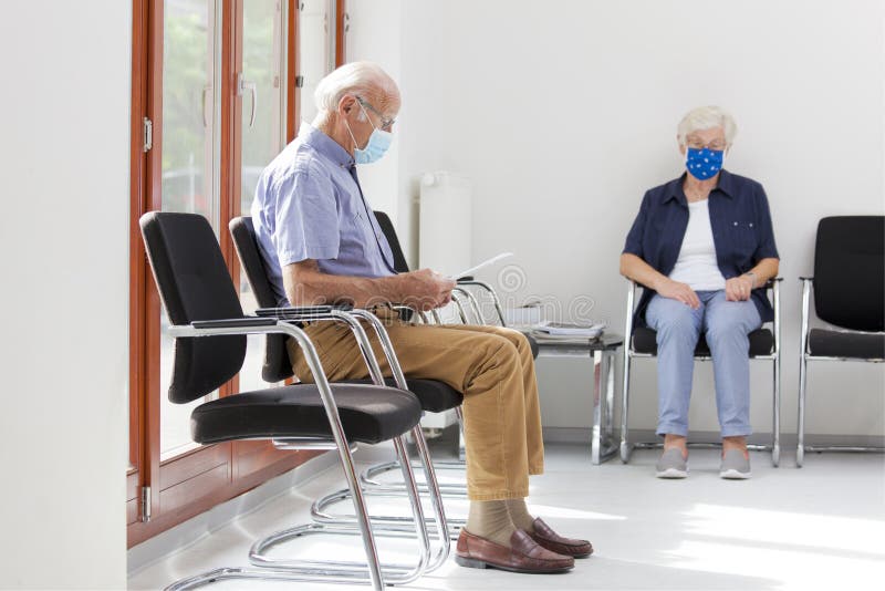 Senior women and men sitting with face masks in a bright waiting room of  a hospital or an office. Senior women and men sitting with face masks in a bright waiting room of  a hospital or an office