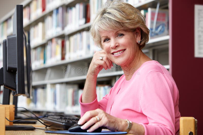 Starsza kobieta pracuje na komputerze w bibliotece zdjęcia stock Starsza kobieta pracuje na komputerze w bibliotece zdjęcia stock