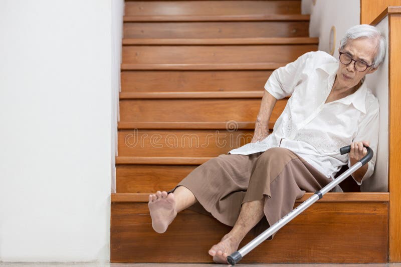 Starsza kobieta siedząca na podłodze klatki schodowej z bólem w biodrach i plecach potknęła się lub straciła równowagę podczas sch