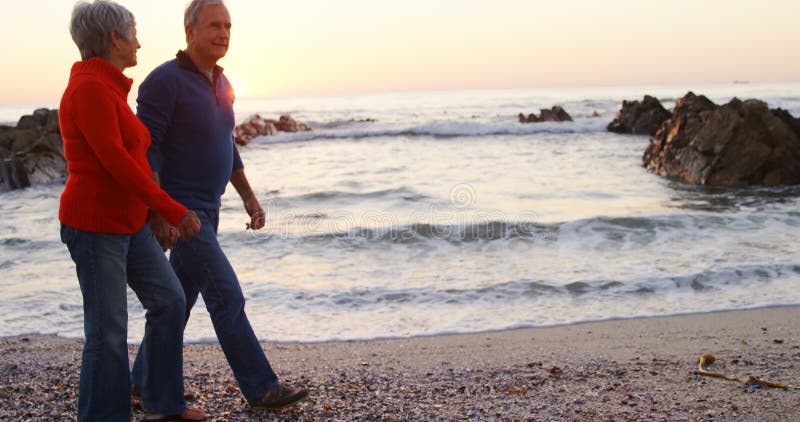 Starsza para chodzi ręka w rękę w plaży 4k
