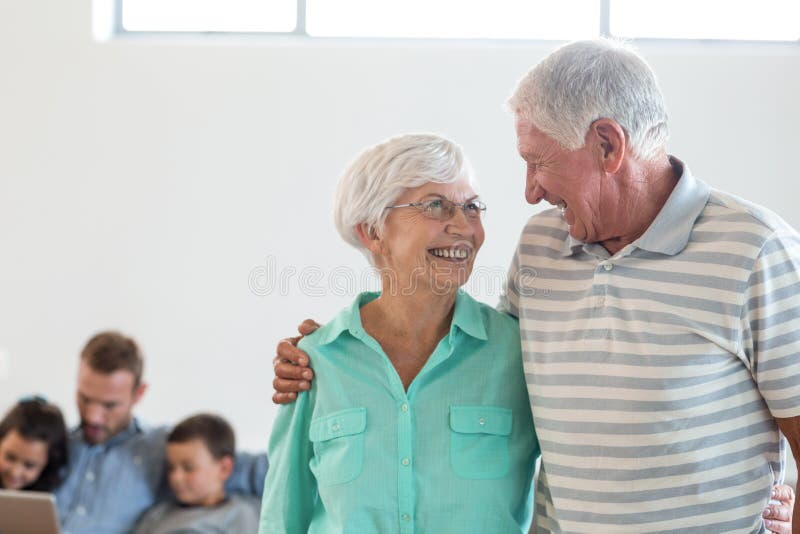 Senior couple embracing each other and smiling in living room. Senior couple embracing each other and smiling in living room