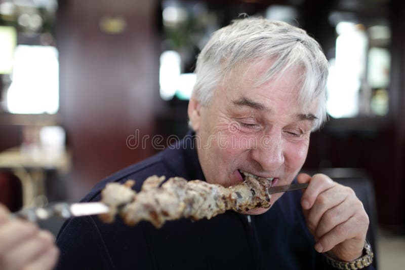 Starszego mężczyzna łasowania kebab na kiju obrazy royalty free Starszego mężczyzna łasowania kebab na kiju obrazy royalty free