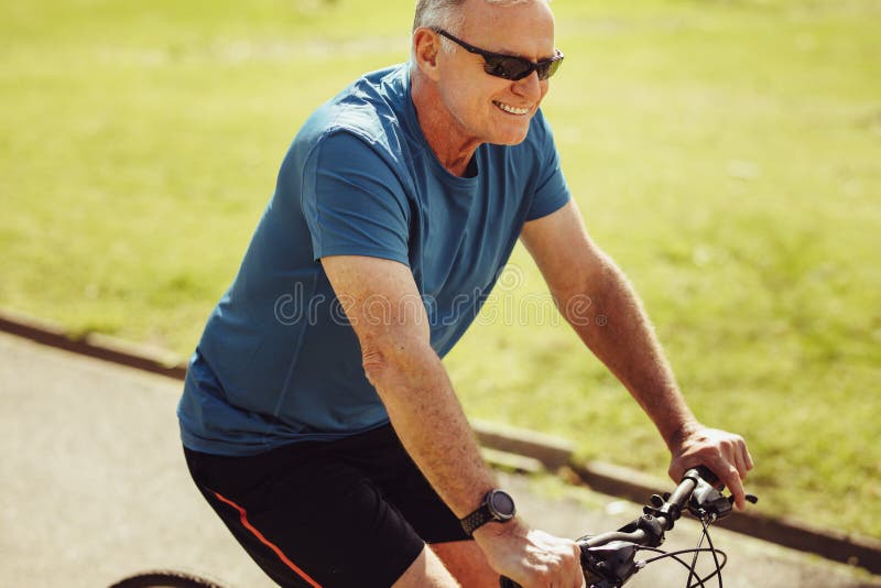 Starszy mężczyzna jedzie bicykl dla sprawności fizycznej fotografia stock Starszy mężczyzna jedzie bicykl dla sprawności fizycznej fotografia stock