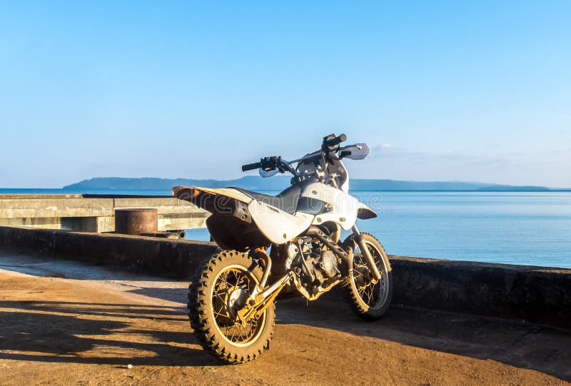 Starta resabegreppet, den gamla lilla vita motorcykeln med det blåa havet och himlen i bakgrund fotografering för bildbyråer Starta resabegreppet, den gamla lilla vita motorcykeln med det blåa havet och himlen i bakgrund fotografering för bildbyråer