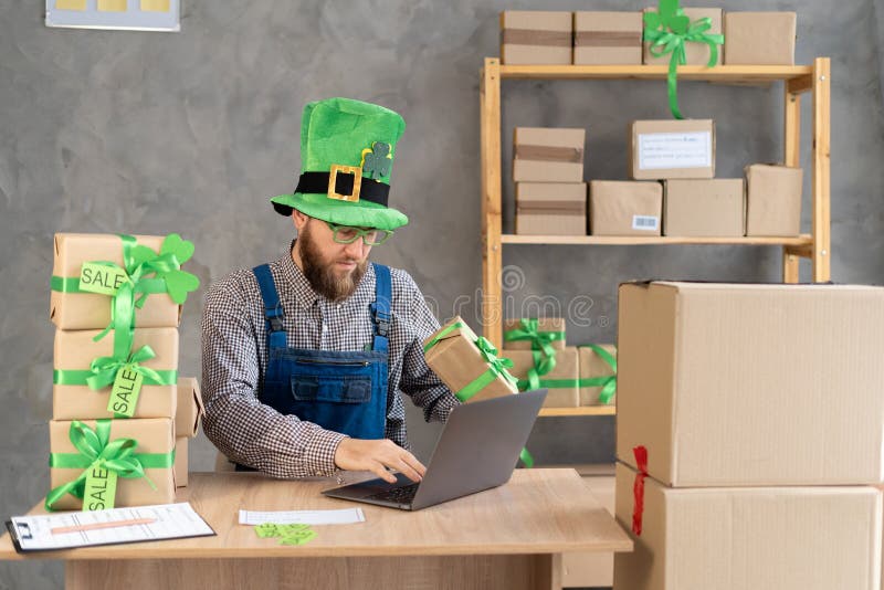 Starta småföretagsägare i leprechaun med hjälp av en bärbar dator på onlinebutiken. Freelance man seller skriver på en bärbar dato royaltyfri bild