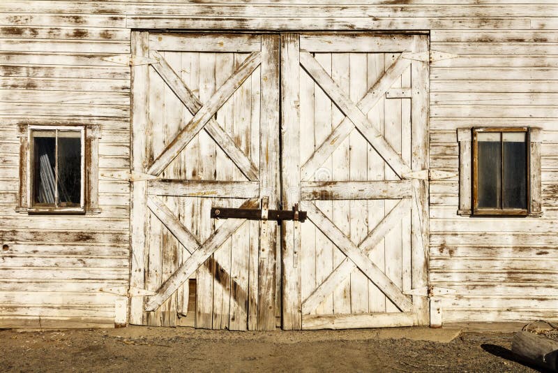 The white painted retro vintage agriculture cow barn yard doors and windows are old dirty filthy door paint and aged farm background pattern. The white painted retro vintage agriculture cow barn yard doors and windows are old dirty filthy door paint and aged farm background pattern.