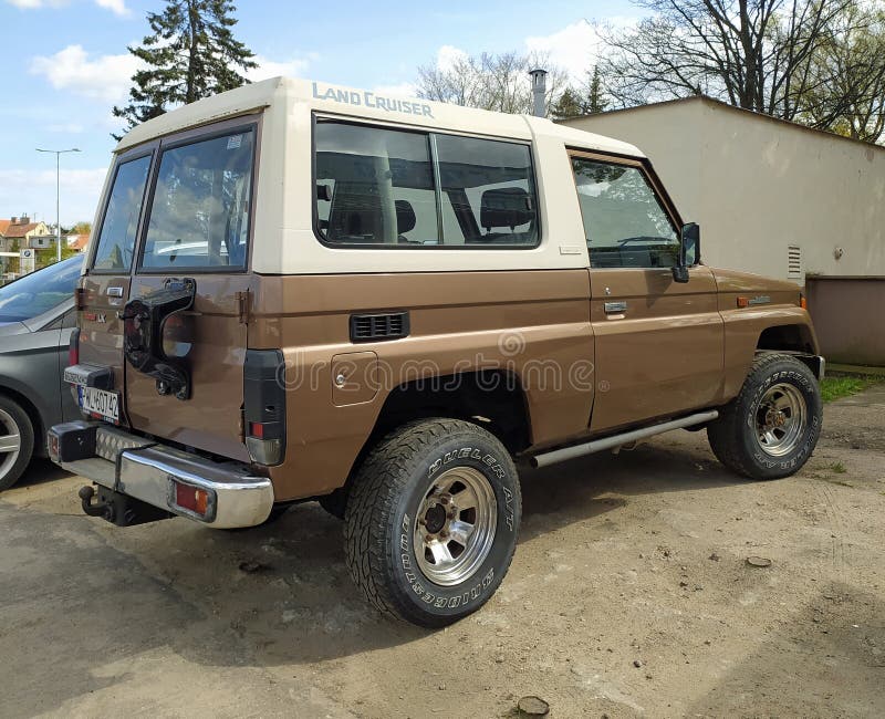 Old brown white offroad four wheel drive classic veteran vintage car Toyota Landcruiser Turbo LX 4WD J70 2-door hardtop parked in Gdansk Wrzeszcz in northern Poland. Right side and rear part view. Fibre reinforced plastic top. Model manufactured from 1984. Modern electric streetcars in the background. April 15th, 2024. Old brown white offroad four wheel drive classic veteran vintage car Toyota Landcruiser Turbo LX 4WD J70 2-door hardtop parked in Gdansk Wrzeszcz in northern Poland. Right side and rear part view. Fibre reinforced plastic top. Model manufactured from 1984. Modern electric streetcars in the background. April 15th, 2024.