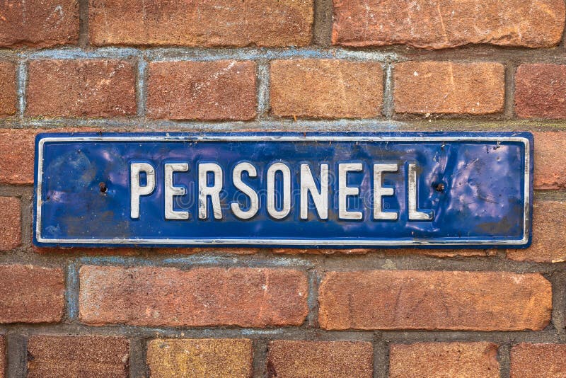Old dented blue sign with the Dutch text Personnel on a brick wall. Old dented blue sign with the Dutch text Personnel on a brick wall