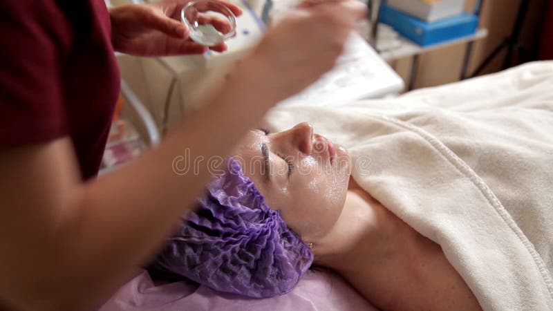 Starzenie si? twarzy traktowanie z kobiety twarzy mask? Cosmetologist stawia nawil? ania gel na twarzy z mu? ni? ciem A zbiory