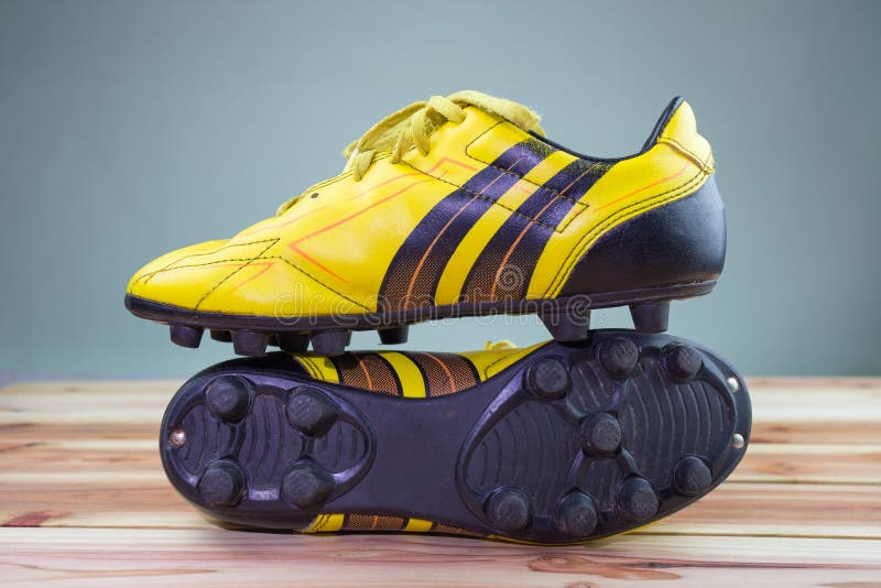 Starzy żółci futbol buty umieszczający na drewnianej desce, szarego tła Miękki światło obraz stock Starzy żółci futbol buty umieszczający na drewnianej desce, szarego tła Miękki światło obraz stock