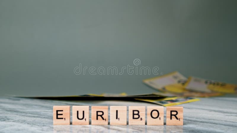 Static Shot of Word EURIBOR Is Written In Wooden Letters On Grey Background. Female Hand Throws 200 Euro Banknotes. Concept of