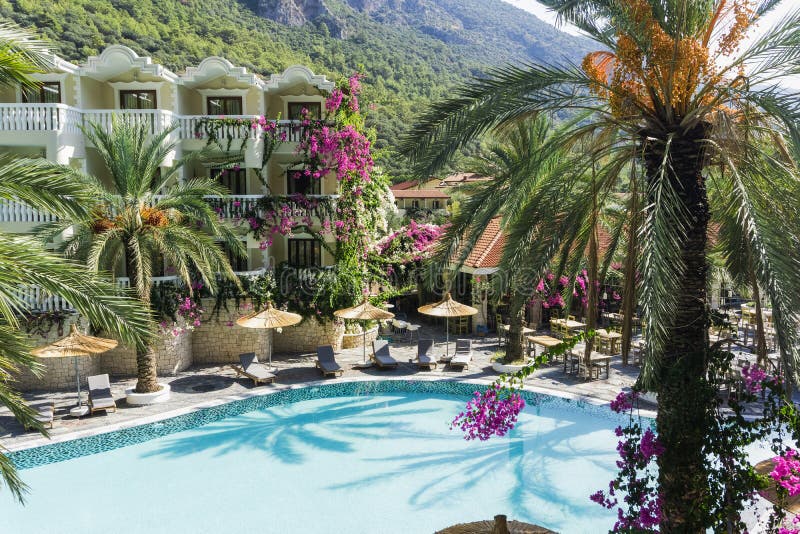 Station balnéaire tropicale de luxe ou villa privée avec parasols et palmiers de chaises longues de la piscine turquoise. Concept