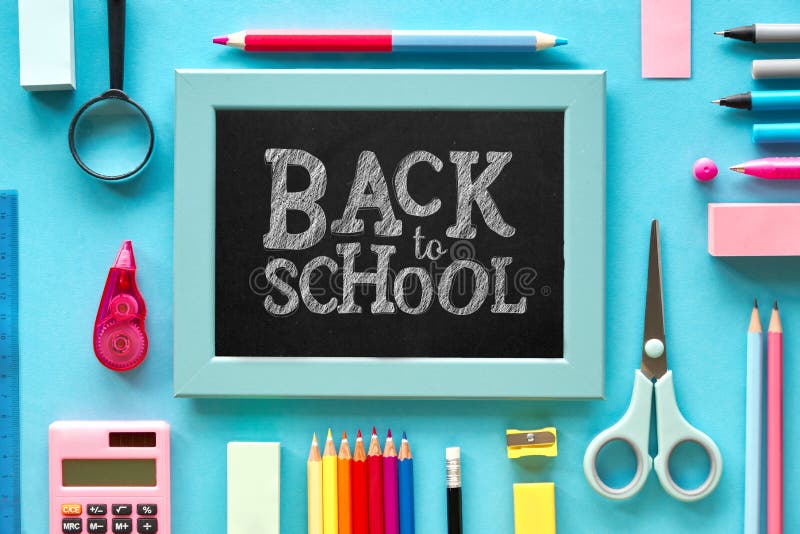 Flat lay concept background \"Back to school\". Stationary items on blue paper background, chalk text on the black board. Flat lay concept background \"Back to school\". Stationary items on blue paper background, chalk text on the black board