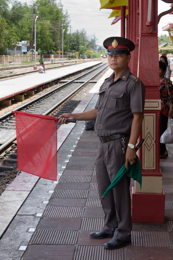 Stationmaster задерживая эмблему революции для того чтобы остановить поезд приходя в железнодорожный вокзал Hua Hin, Prachuap Khi стоковое фото rf Stationmaster задерживая эмблему революции для того чтобы остановить поезд приходя в железнодорожный вокзал Hua Hin, Prachuap Khi стоковое фото rf
