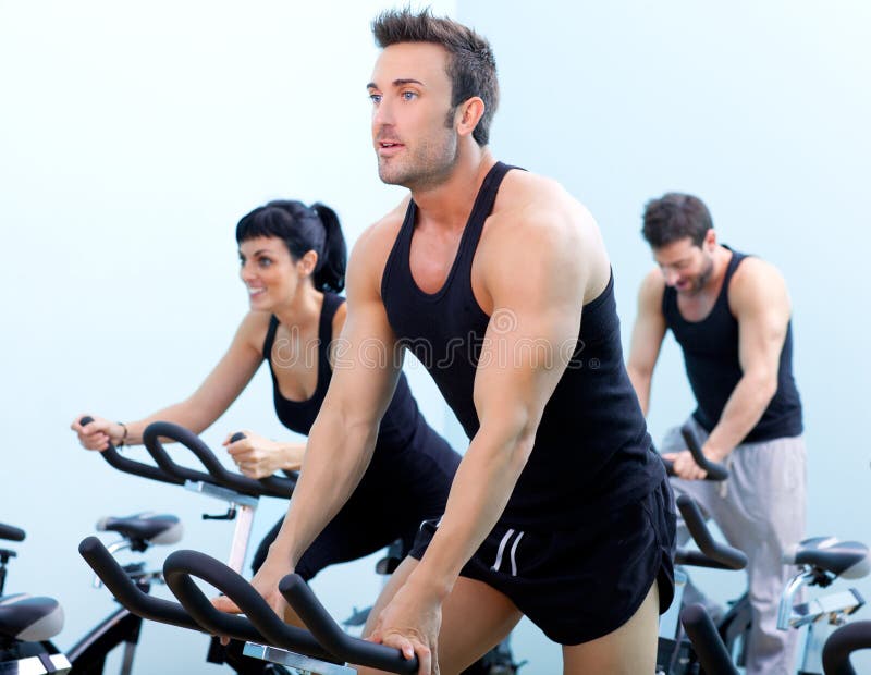 Stationary spinning bicycles fitness men in a gym sport club. Stationary spinning bicycles fitness men in a gym sport club