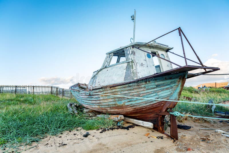 Statku starzy drewniani stojaki na piaskowatej plaży. Stary drewniany statek rzucający na piaskowatej plaży, niebieskie niebo, jasny pogodna pogoda Teriberka wioska, północ Rosja Barents morze Arktyczny ocean