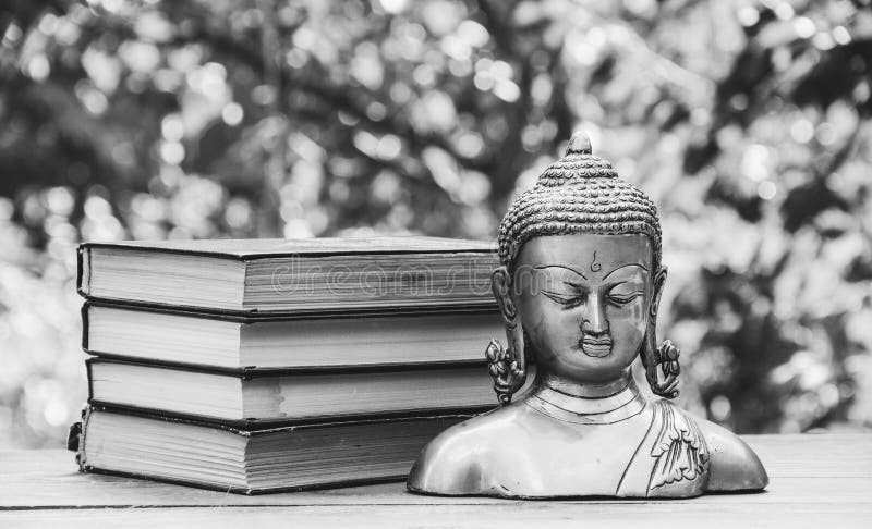 Statua antica di Buddha e una pila di libri Religione e cultura fotografia stock Statua antica di Buddha e una pila di libri Religione e cultura fotografia stock