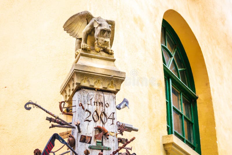 Statua del doccione sopra un palo di legno, accanto ad una struttura della finestra incurvata con i dettagli verdi, con una paret fotografia stock libera da diritti Statua del doccione sopra un palo di legno, accanto ad una struttura della finestra incurvata con i dettagli verdi, con una paret fotografia stock libera da diritti