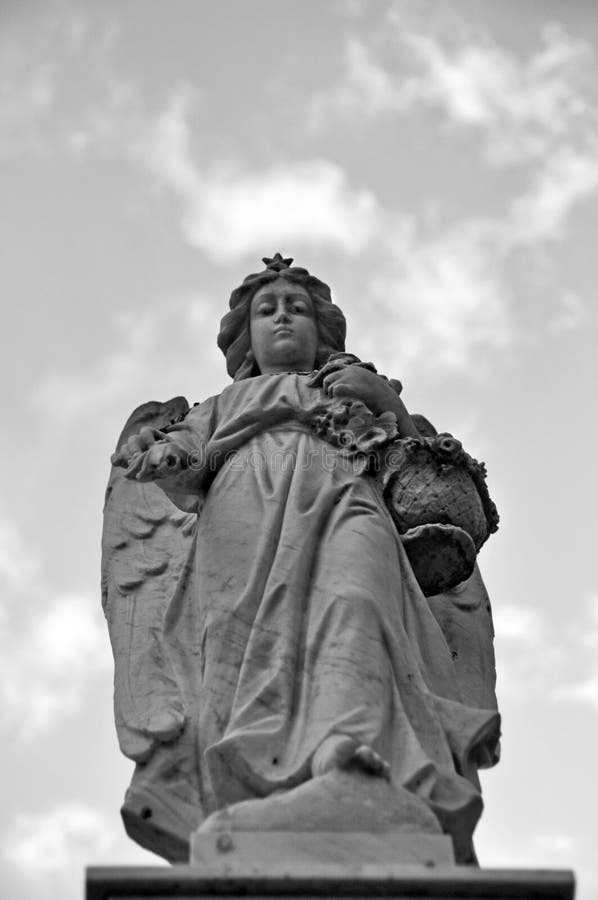 Statue of Angel looking down in cemetery in black and white stock photography Statue of Angel looking down in cemetery in black and white stock photography