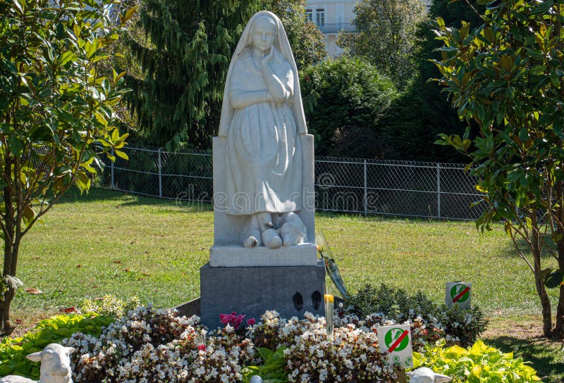 Statue of Bernadette Praying To Our Lady of Lourdes with Flowers Next