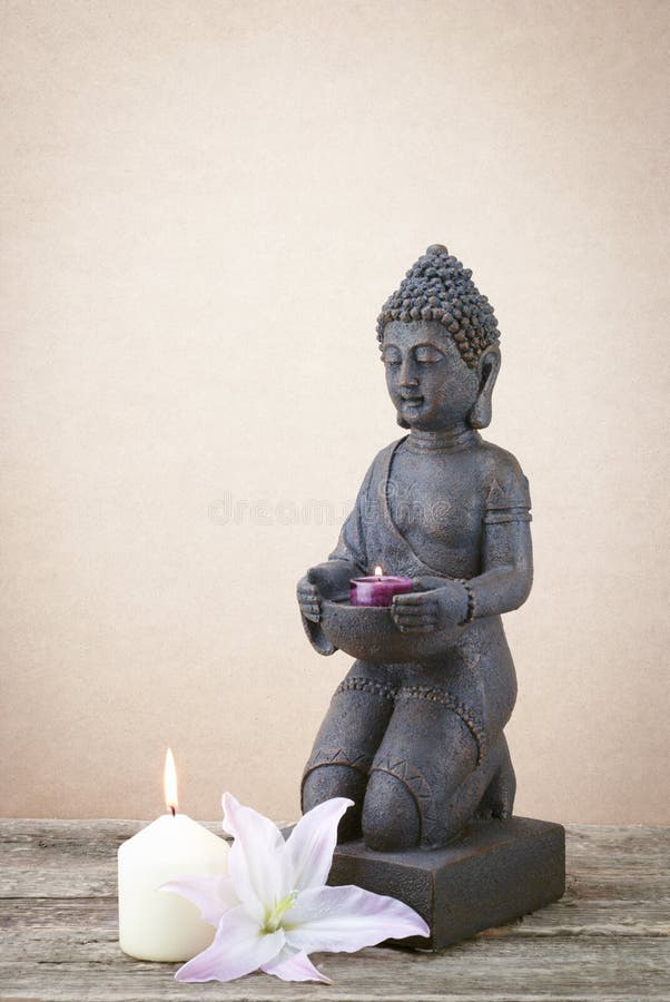 Statue of Buddha with a Candle His Hand on a Beige Background Stock