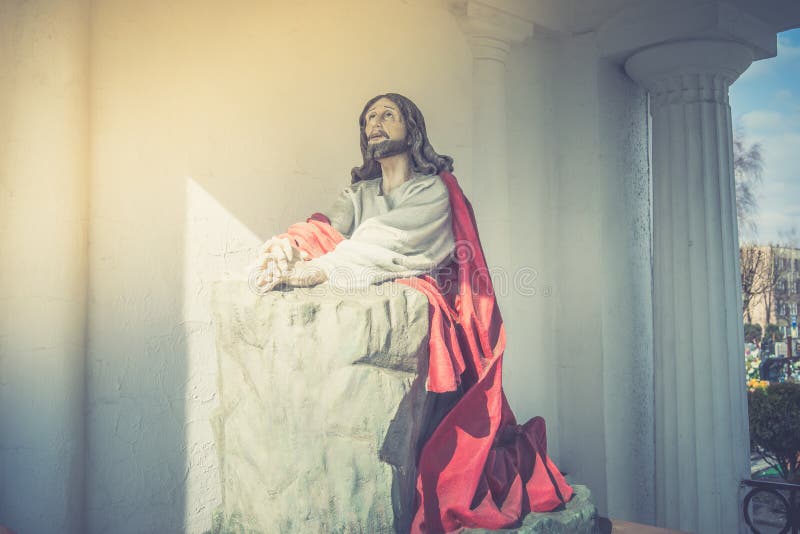 Statue de jésus-christ priant à genoux et regardant vers le haut dans une église photo stock