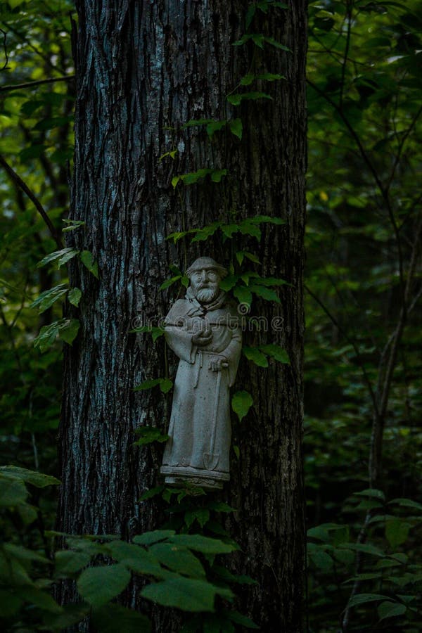 Statue eines alten Mannes an einer Baumrinde befestigt. lizenzfreies stockfoto