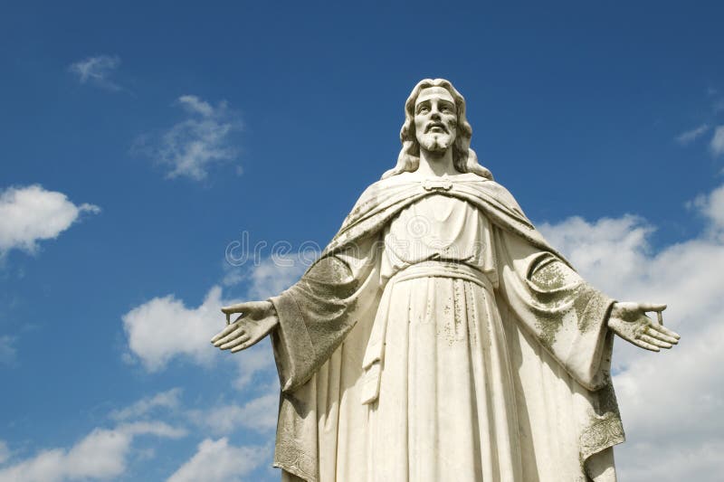 A statue of Jesus with open arms and beautiful deep blue sky background with white clouds, horizontal with copy space. A statue of Jesus with open arms and beautiful deep blue sky background with white clouds, horizontal with copy space