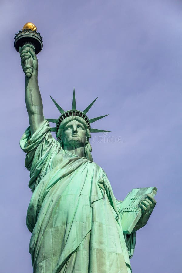 The Statue of Liberty a colossal neoclassical copper sculpture on Liberty Island, New York Harbor, NYC.Back view against blue sky