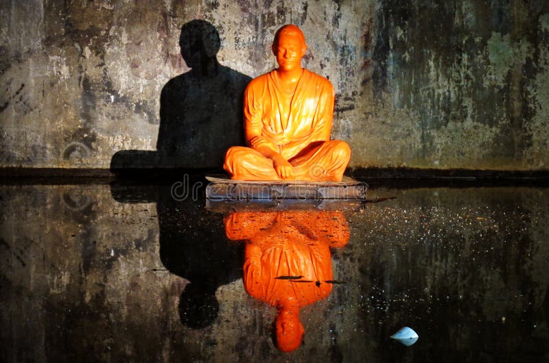 Statue of orange monk sitting in a cave royalty free stock photography Statue of orange monk sitting in a cave royalty free stock photography