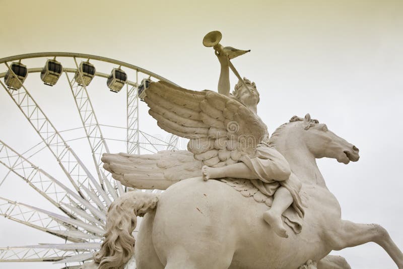 A sculpture in the Jardin Des Tuileries next to Place de la Concorde with its giant ferris wheel. A sculpture in the Jardin Des Tuileries next to Place de la Concorde with its giant ferris wheel