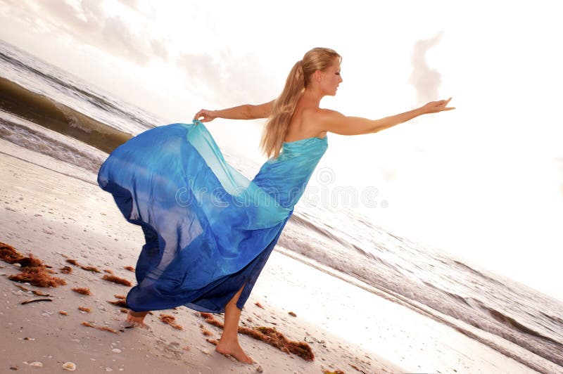 Žena tanečník je pózování v profil paže vyvýšený kouká na její otevřít ruka na pláž vlny shazovat v, v bohyně jako póza.