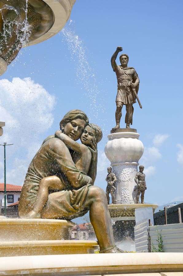 Staty av modern & son och staty av Alexander det stort i bakgrund, i mitt av Skopje arkivfoto Staty av modern & son och staty av Alexander det stort i bakgrund, i mitt av Skopje arkivfoto