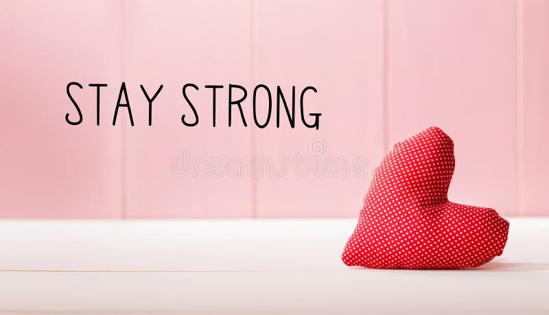 Stay Strong message with a red heart cushion over a pink wooden wall