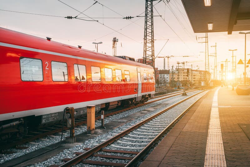 Stazione ferroviaria bella con il treno pendolare rosso moderno al tramonto fotografia stock Stazione ferroviaria bella con il treno pendolare rosso moderno al tramonto fotografia stock