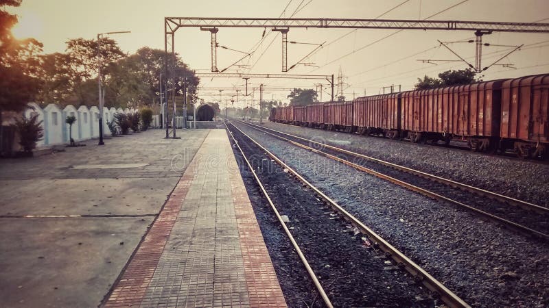 Stazione ferroviaria indiana vuota durante il goodstrain del trainsunset delle merci di tramonto fotografie stock libere da diritti Stazione ferroviaria indiana vuota durante il goodstrain del trainsunset delle merci di tramonto fotografie stock libere da diritti